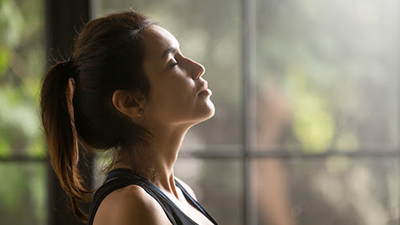 female with eyes closed next to window meditating