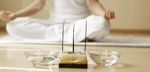 female meditating with candles and insence