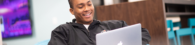 student with laptop sitting in comfy chair smiling