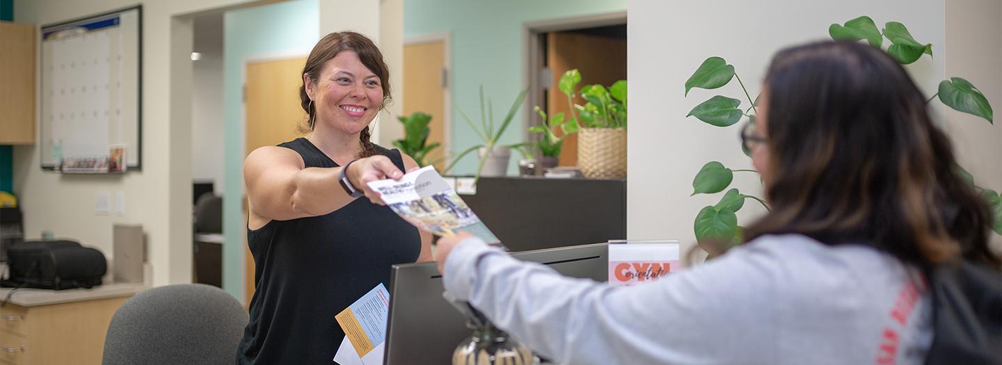 Student receiving brochures at the front desk