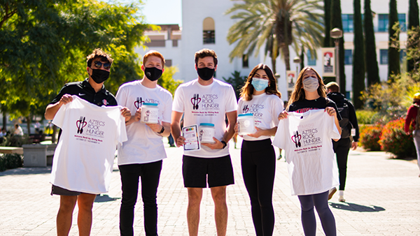 students holding their aztecs rock hunger tshirts