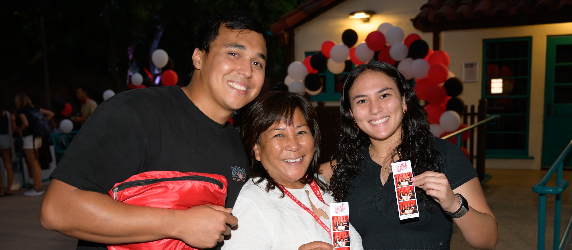 family holding photobooth images with New Parent and Student Programs family weekend logo on it.