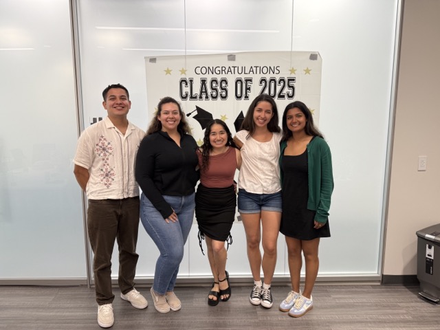 Interns posing in front of a glass partition
