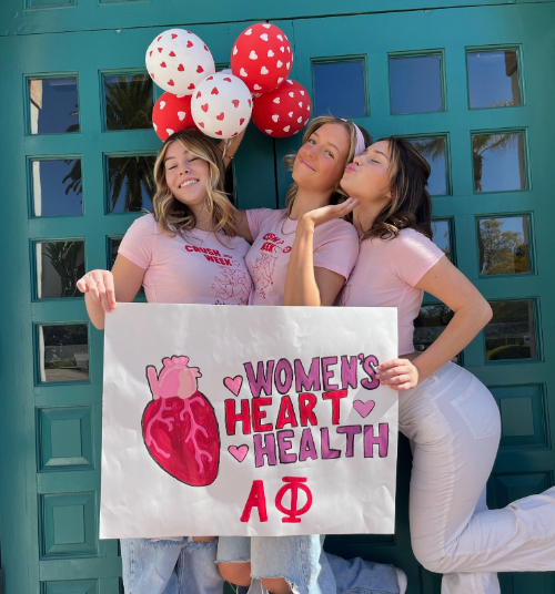 APhi members pose with a sign reading Women's Heart Health.