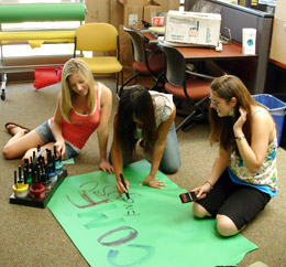 students sitting on floor making posters